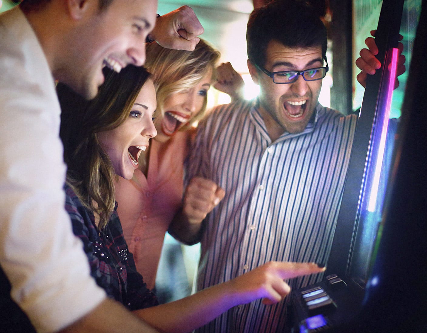Four individuals engaged in playing a slot machine, displaying expressions of anticipation and enjoyment.